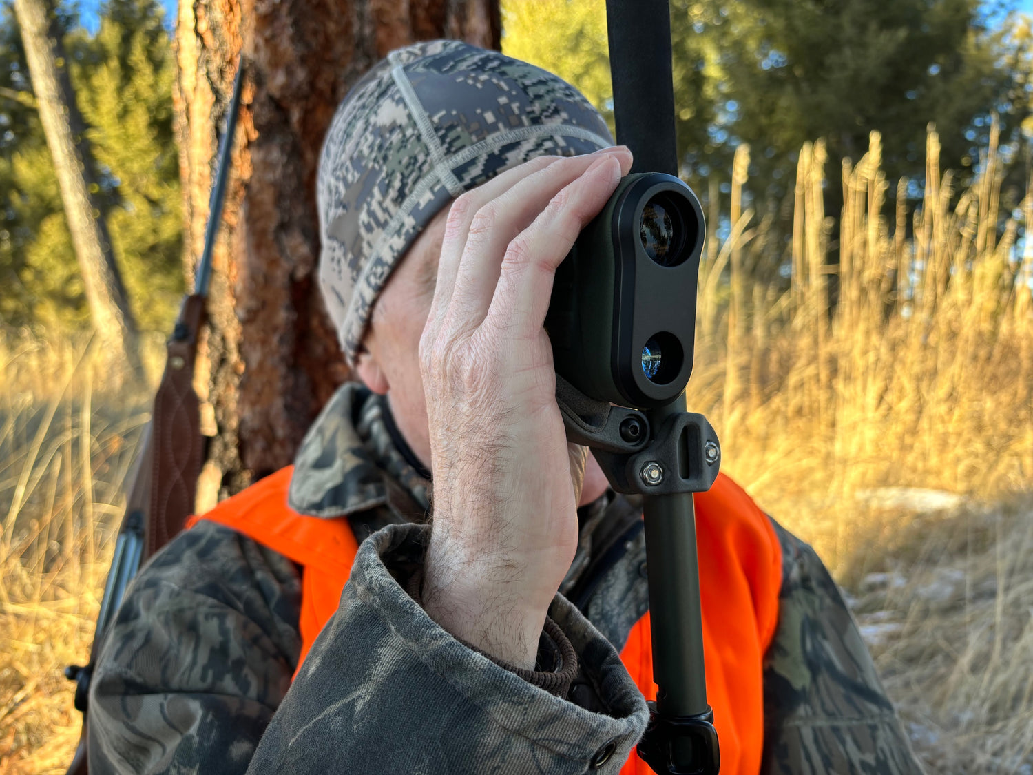 A hunter using the roadrunner rifle rest attached to a trekking pole to stabilize a range finder.