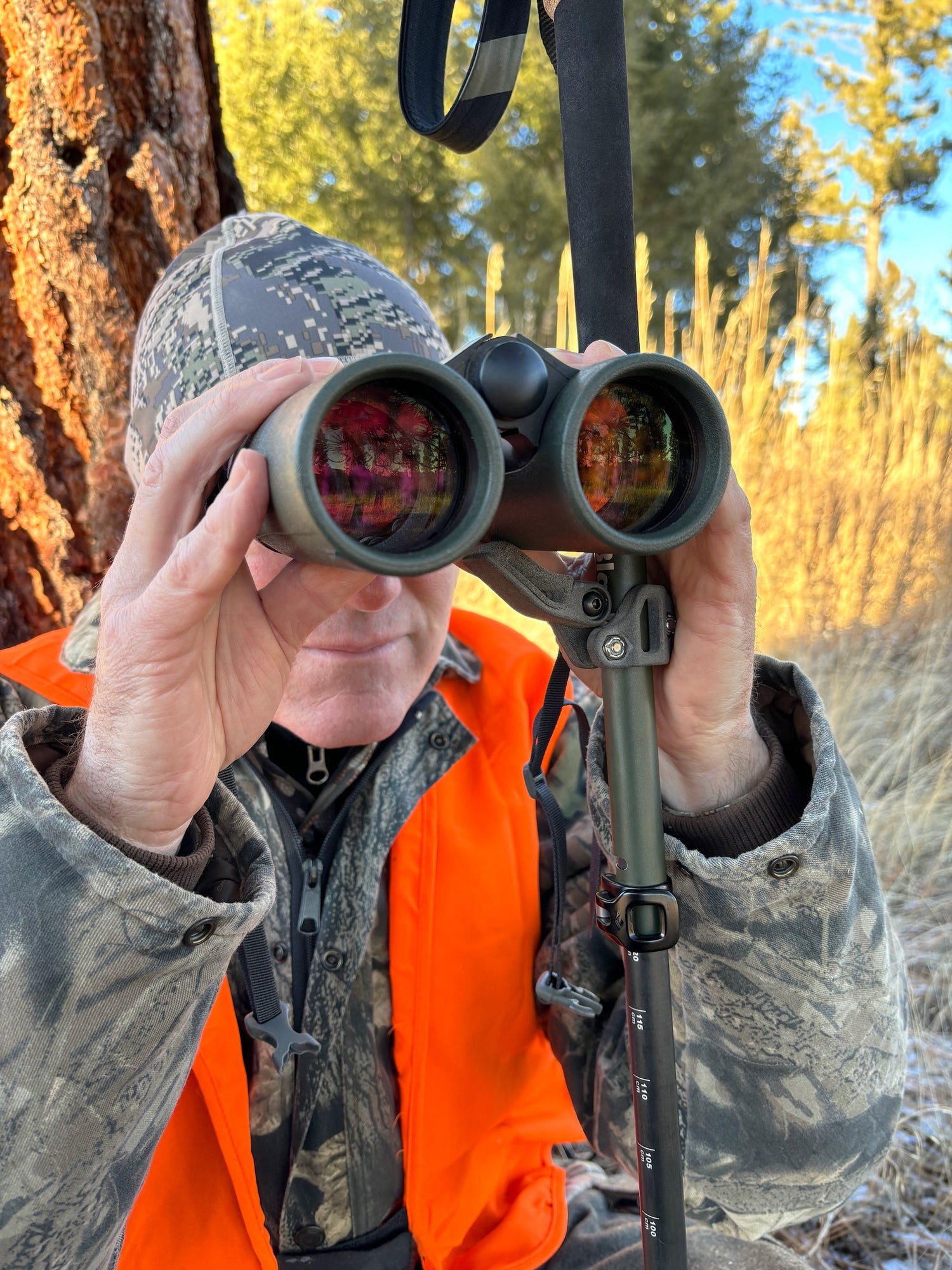 A hunter using the roadrunner rifle rest attached to a trekking pole to stabilize binoculars.